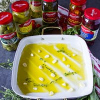 An oven pan with olive oil and sliced garlic and fresh thyme
