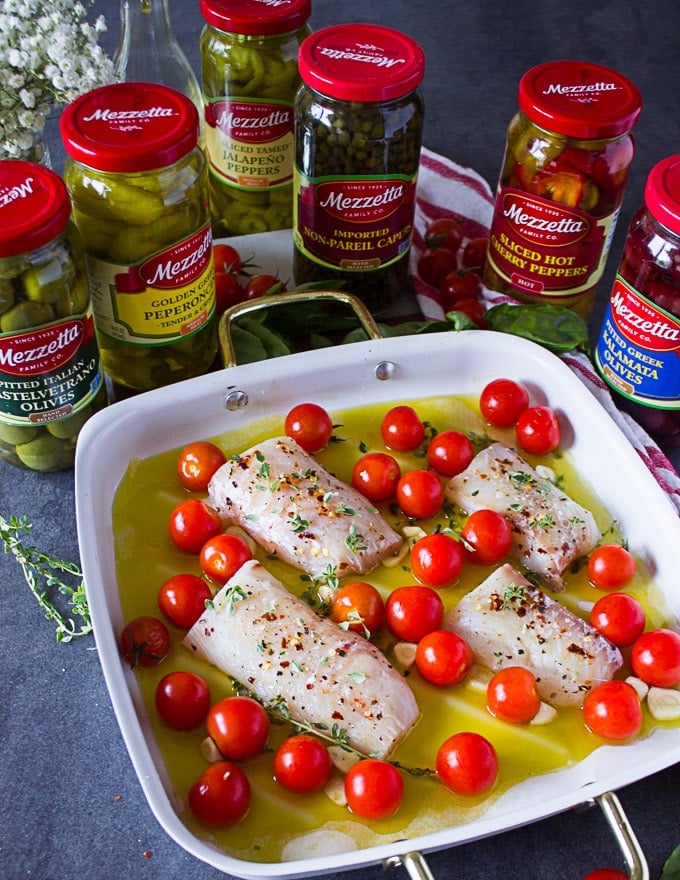 The raw fish placed over the garlic surrounded by tomatoes