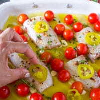 A hand placing the jalapenos over the fish