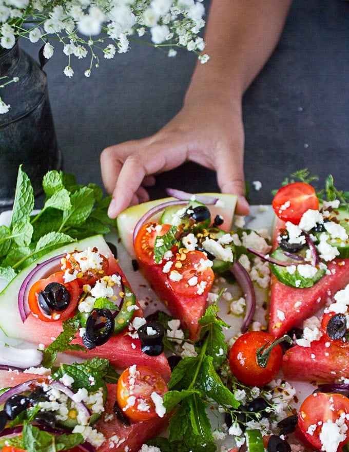 A little hand picking up a watermelon salad slice