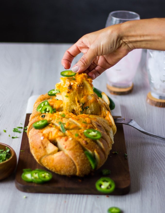 A hand pulling apart the pull apart bread put of the oven