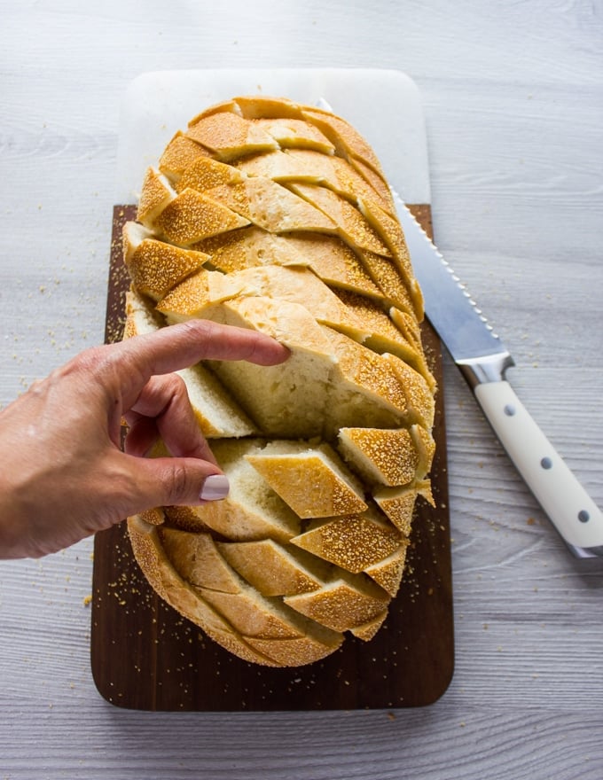 A hand showing the final slits in the bread sliced and ready for the toppings