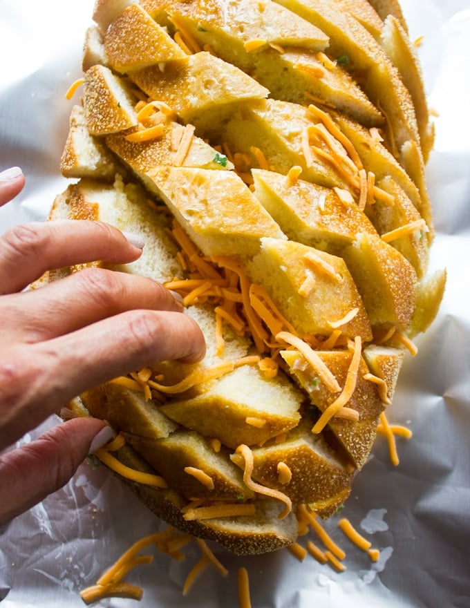 A hand layering the bottom layer of cheese in the pull apart bread