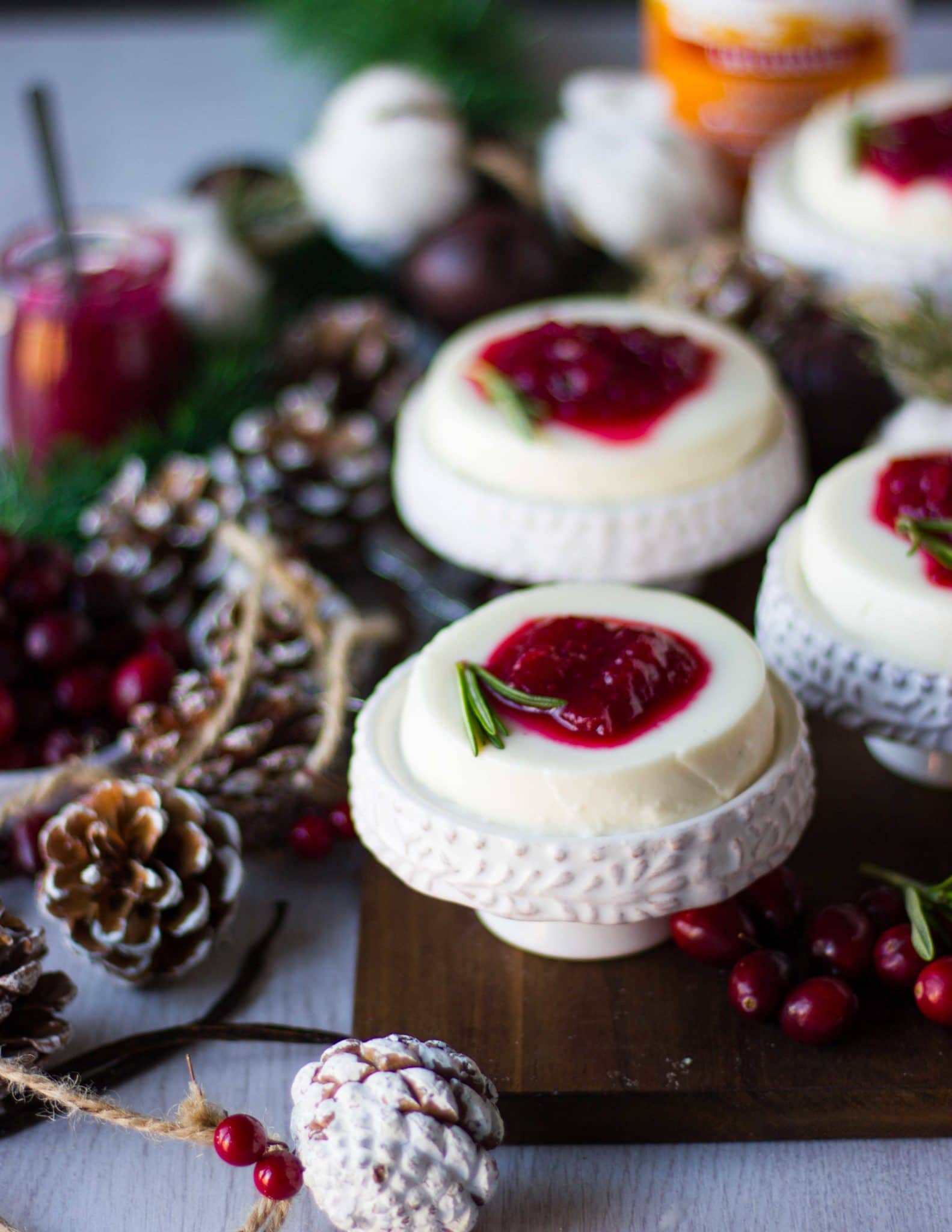 serving the panna cotta on a serving plate over a wooden board with cranberry sauce and rosemary sprigs