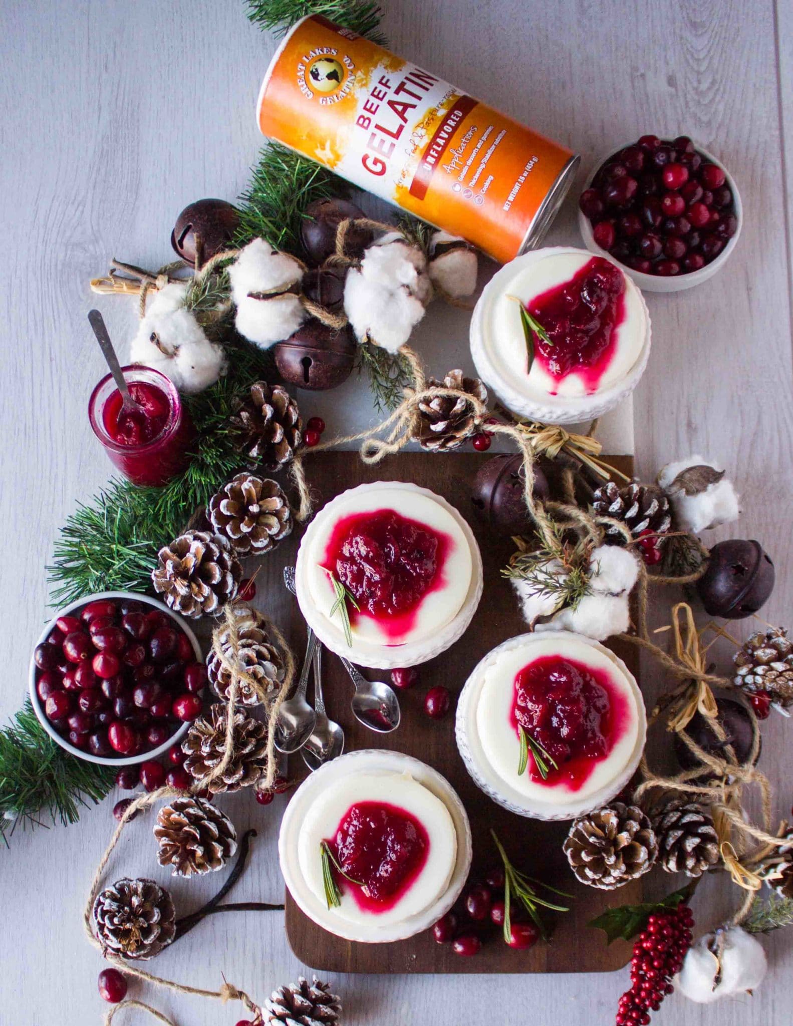 top view of a holiday dessert with tree cones, fresh cranberries and rosemary and 4 panna cotta desserts on serving plates with gelatin