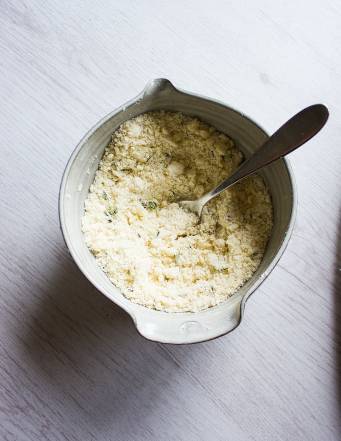A bowl with the gratin toppings mixed together with a fork : flour, butter, parmesan cheese, salt and fresh thyme 