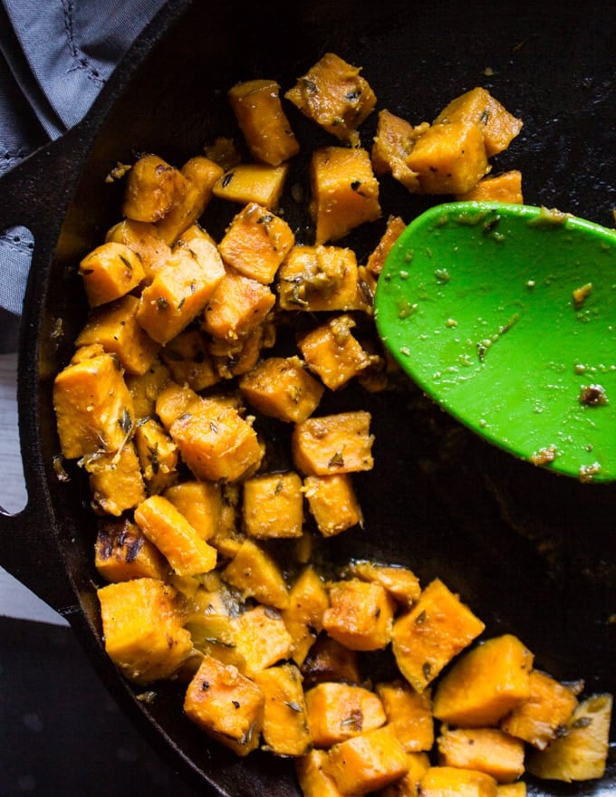 A pan and spatula cooking the sweet potatoes in a skillet 