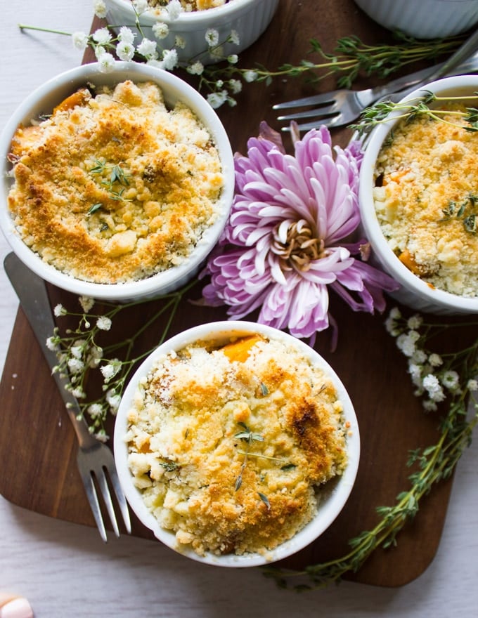 Three sweet potato gratins on a cutting board surrounded by a fork and flower.