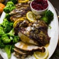 turkey berast recipe, sliced and drizzled with gravy showing one slice in a serving plate with broccoli and lemon slices