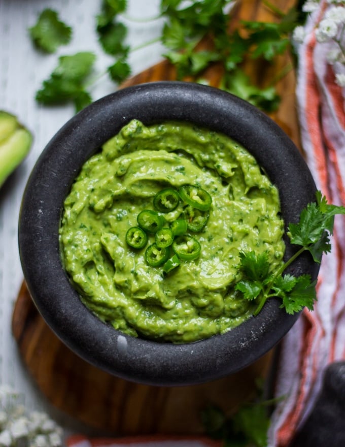 Close up of a bowl for authentic  guacamole  recipe topped with jalapenos 
