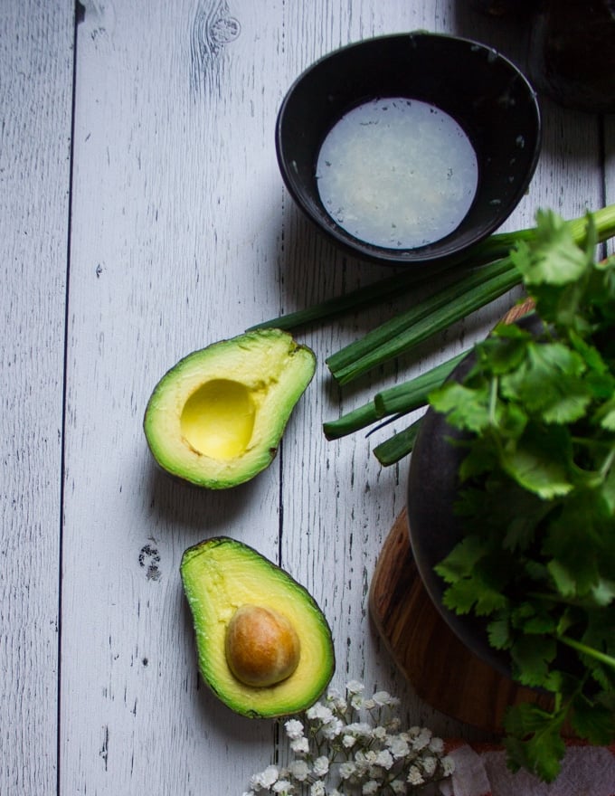 Avocados cut in half and cilantro on a white board