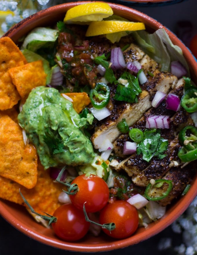 close up of the fajita bowl made using lettuce and chips and layered with chicken, guacamole, salsa and fresh ingredients 