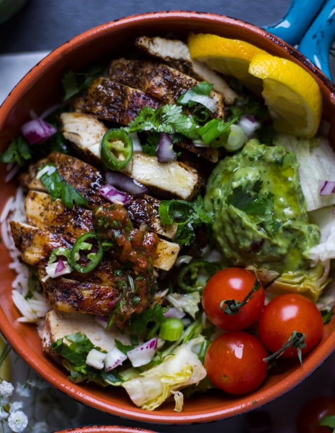 A fajita bowl loaded with chicken fajitas, rice, tomatoes guacamole and salsa