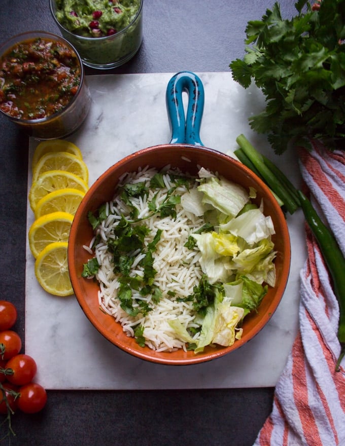 A bowl ready to be assembled with a layer of herbed rice at the bottom and some lettuce