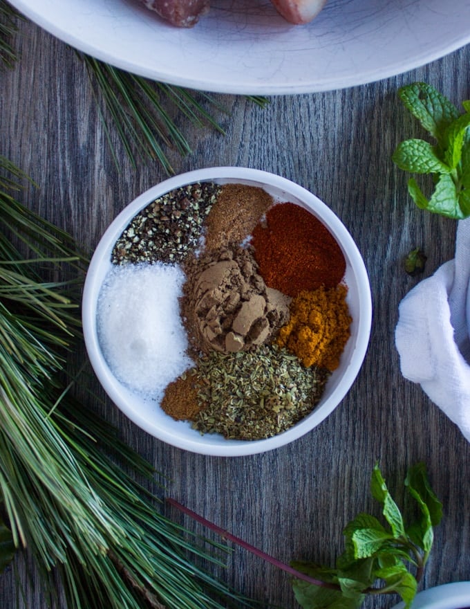 A plate with a collection of Moroccan Spices including: turmeric, nutmeg, allspice, paprika, salt pepper, oregano, cinnamon 