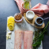 Ingredients for baked mahi mahi recipe including: 2 mahi mahi fish fillet defrosted, salt and pepper, chilli flakes, fresh herbs, garlic and lemon slices, and butter