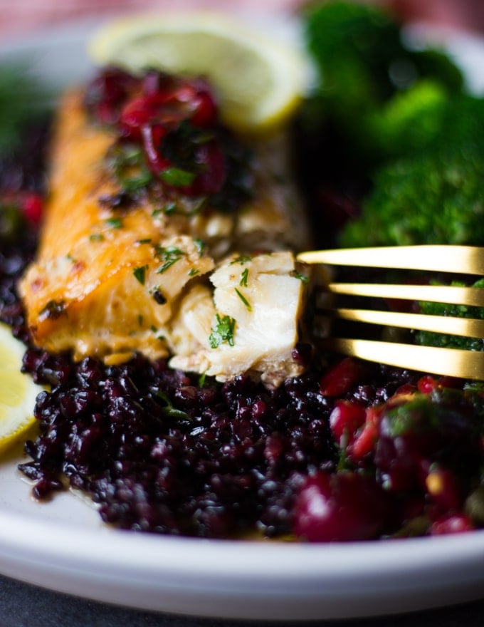 A fork breaking into the baked mahi mahi recipe to show the flakey texture of the oven baked fish