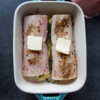 seasoned mahi mahi fish over the baking dish with a dab of butter ontop ready to go to bake in the oven