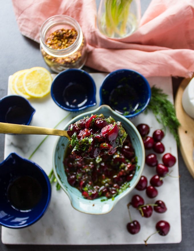 A spoon holding off the ready cherry salsa to show the texture of it