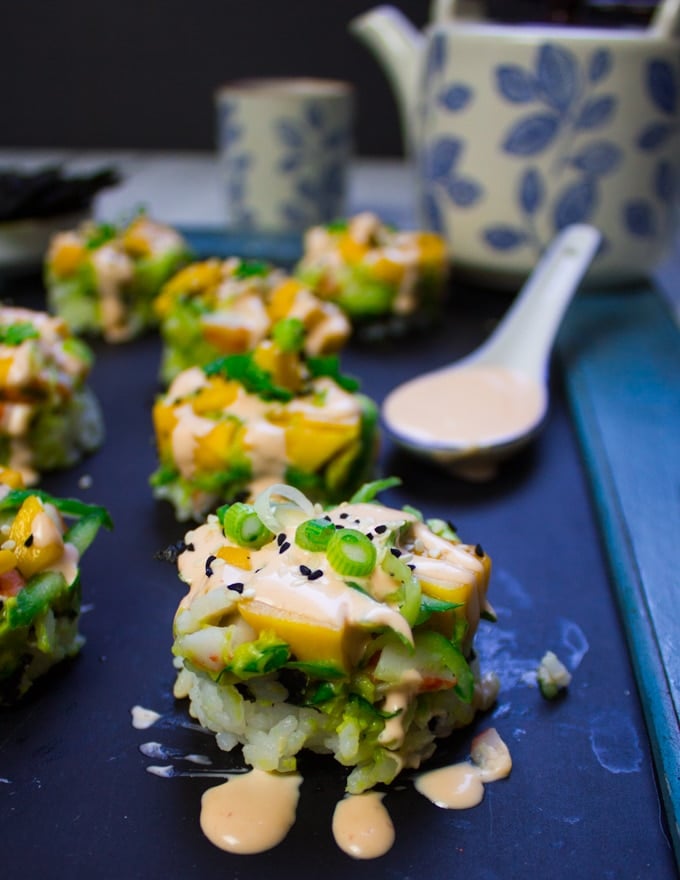 Close up of two crab sushi made into sushi stacks with a drizzle of spicy mayo dripping all around the sushi stack