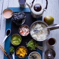 Ingredients for the crab sushi and sushi stacks, a pot of rice, seaweed sheets, spicy mayo, soy sauce, crab meat, mashed avocado, mango, scallions, shredded cucumbers, sesame seeds, dry measuring cups