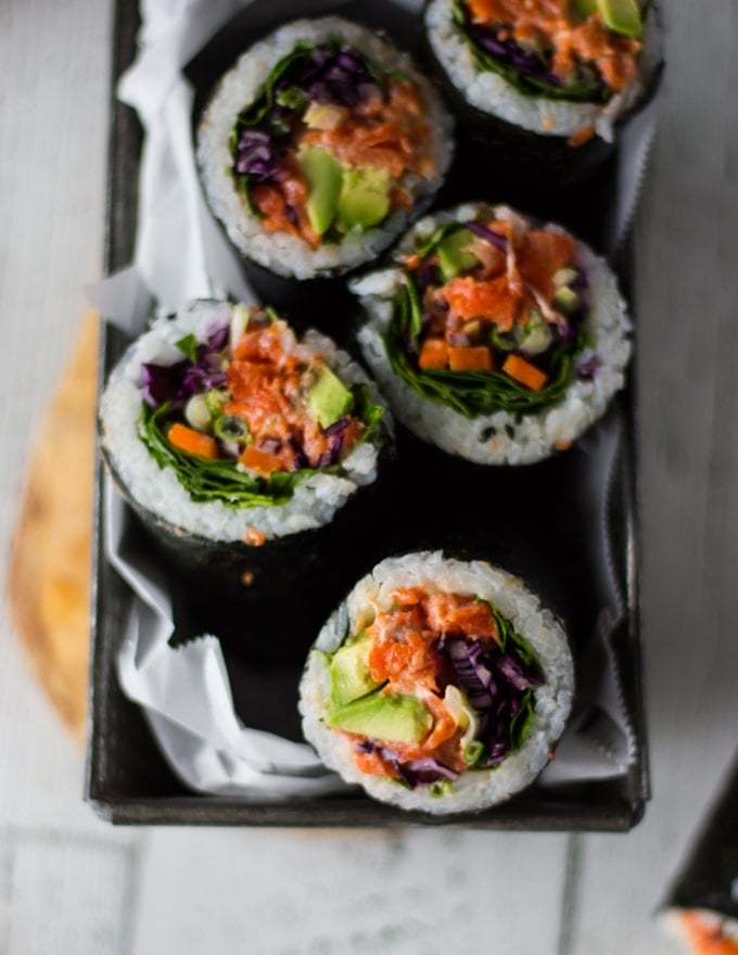 A plate with a few sushi burritos sliced up showing the fillings and layers in the roll close up