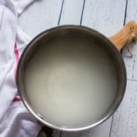 A pot with boiling water and the sushi rice added in to cook