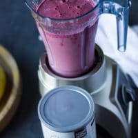 A blender with the cherry smoothie layer finished and thick