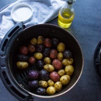 Seasoned potatoes in a single layer int he air fryer basket ready to be air fried