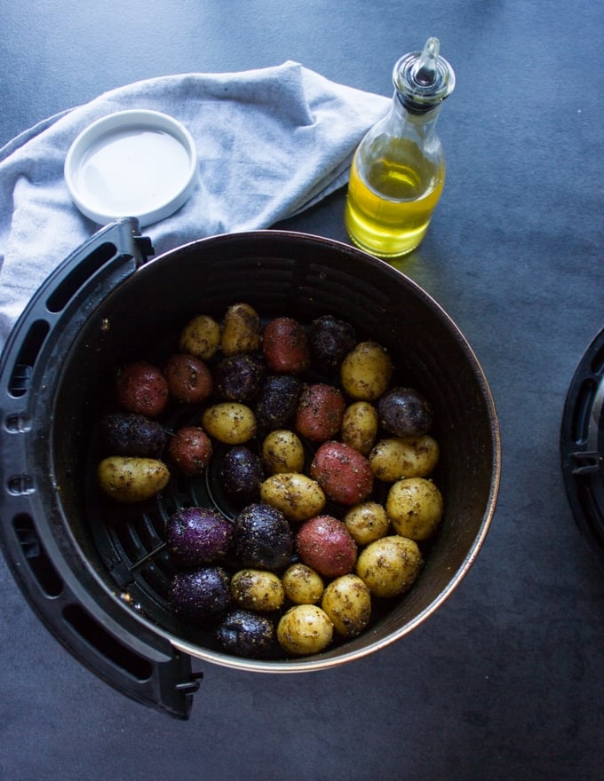 Seasoned potatoes in a single layer int he air fryer basket ready to be air fried 