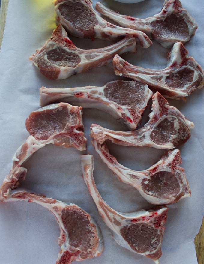 Raw lamb chops on a parchment paper, trimmed
