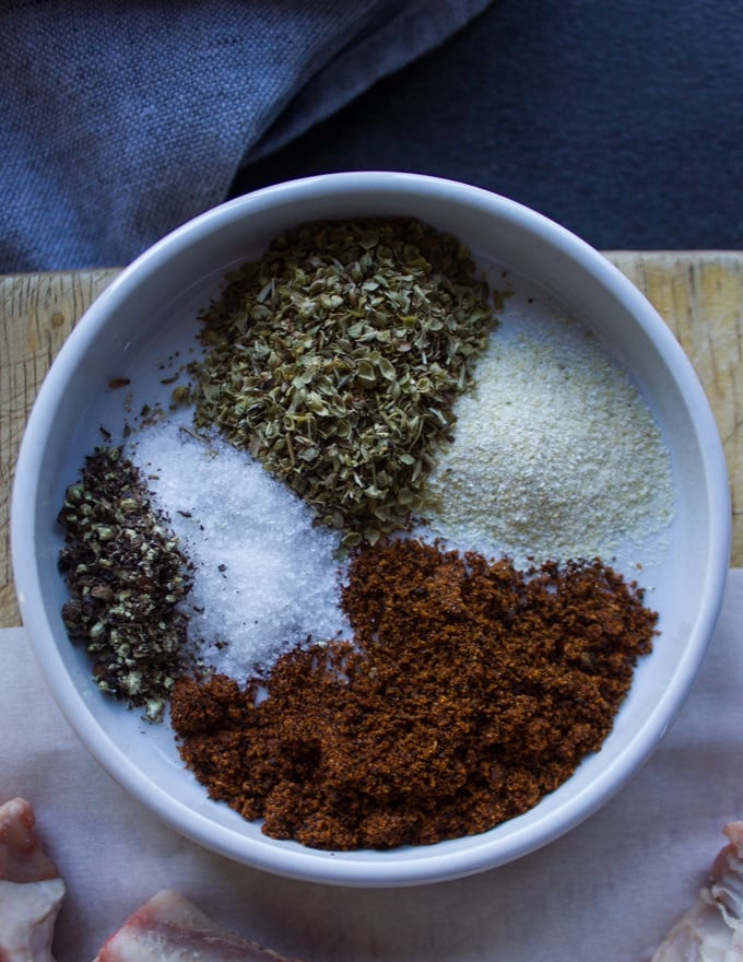 A plate with seasoning spices including salt, pepper, chilli powder, oregano and onion powder 