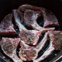 Lamb Chops seasoned and arranged in the air fryer basket in a single layer ready to air fry