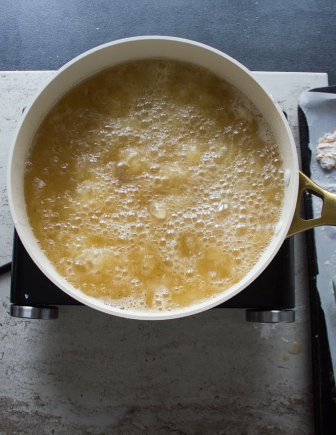 Oil bubbling in a skillet and fish frying inside