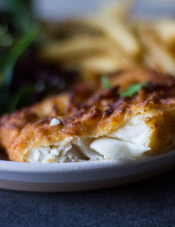 A cut up piece of fried fish showing the inside texture of flakey moist fish