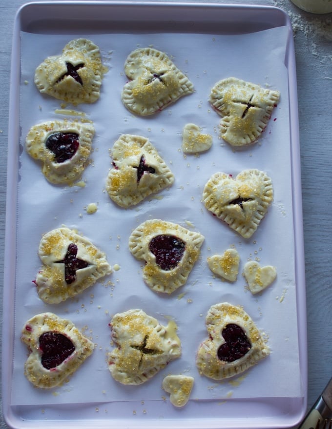 A tray of mini cherry pies going into the oven 