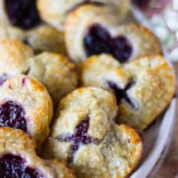 Out of the oven mini cherry pies stacked in a white plate close up showing the texture of the pies