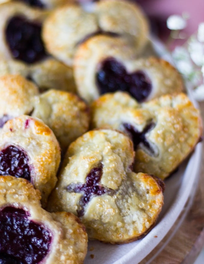 Out of the oven mini cherry pies stacked in a white plate close up showing the texture of the pies