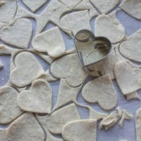 a heart cookie cutter cutting out the pie dough into small pies