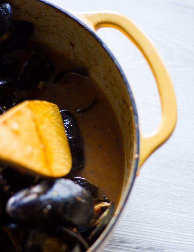 A spoon showing off the sauce at the pan after mussels have cooked