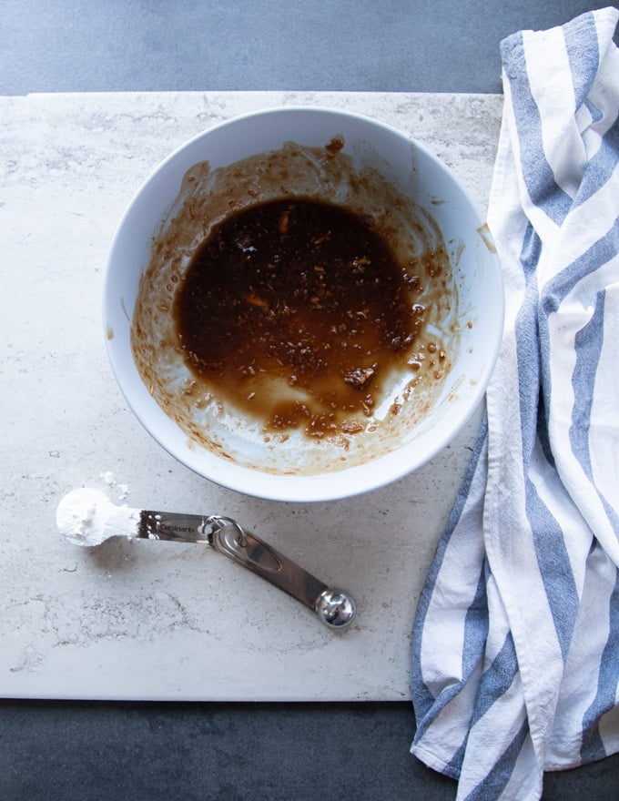 remaining marinade in a bowl with a tablespoon of cornstarch on a marble ready to be added and then coking with the beef tips recipe