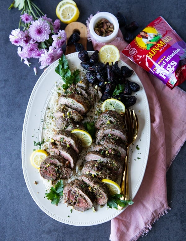 A huge serving plate of boneless leg of lamb roasted and sliced, stuffed with feta, figs and pistachios and surrounded by orchard valley figs