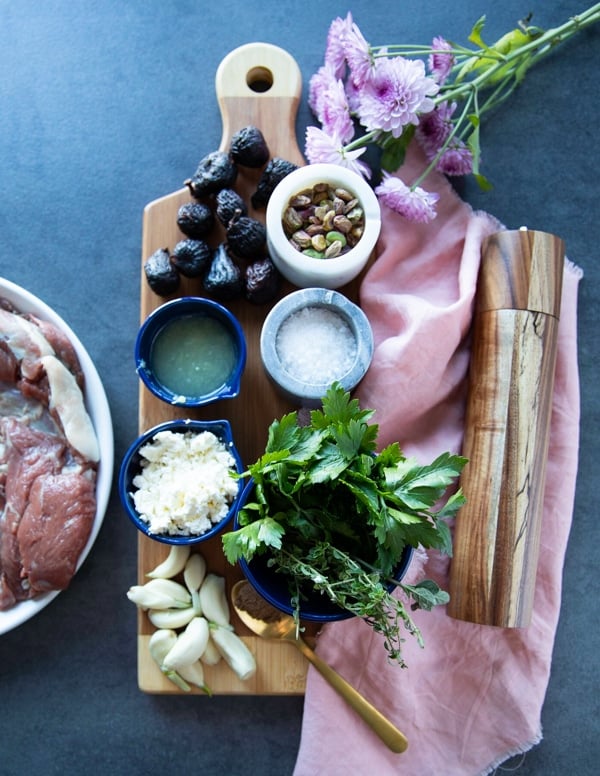 Ingredients for boneless leg of lamb recipe including the leg of lamb, lemon juice, olive oil, salt and pepper, herbs, dried figs, pistachio, feta cheese and garlic 