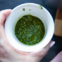 A hand holding a bowl of the marinade for the boneless leg of lamb