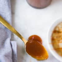 A spoon with homemade caramel sauce on a white marble showing the silky texture
