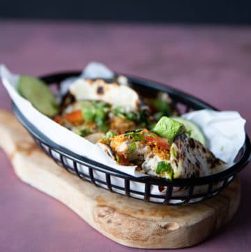 Air fryer fish made into tacos showing a piece of bitten fish to see how succulent and juicy the fish is