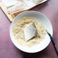 coating the fillet in Panko bread crumbs mixture with tongs.