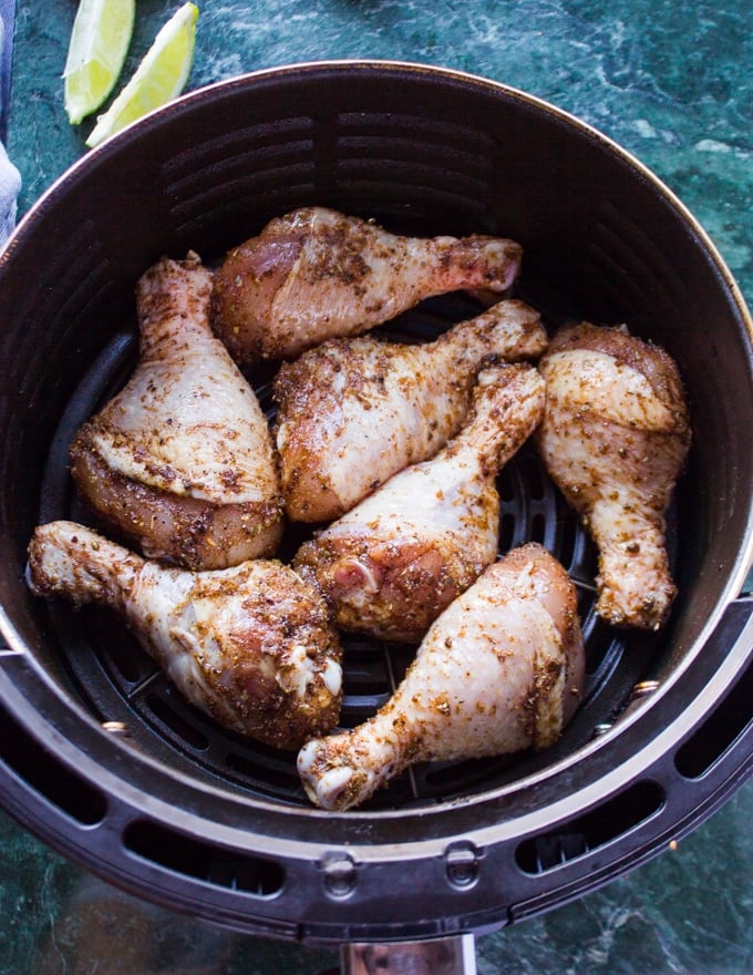 chicken legs coated with the spice mix and placed in an air fryer basket ready to air fry