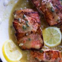 sockeye salmon recipe in a pan with lemon butter sauce and lemon slices cooked