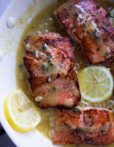 sockeye salmon recipe in a pan with lemon butter sauce and lemon slices cooked